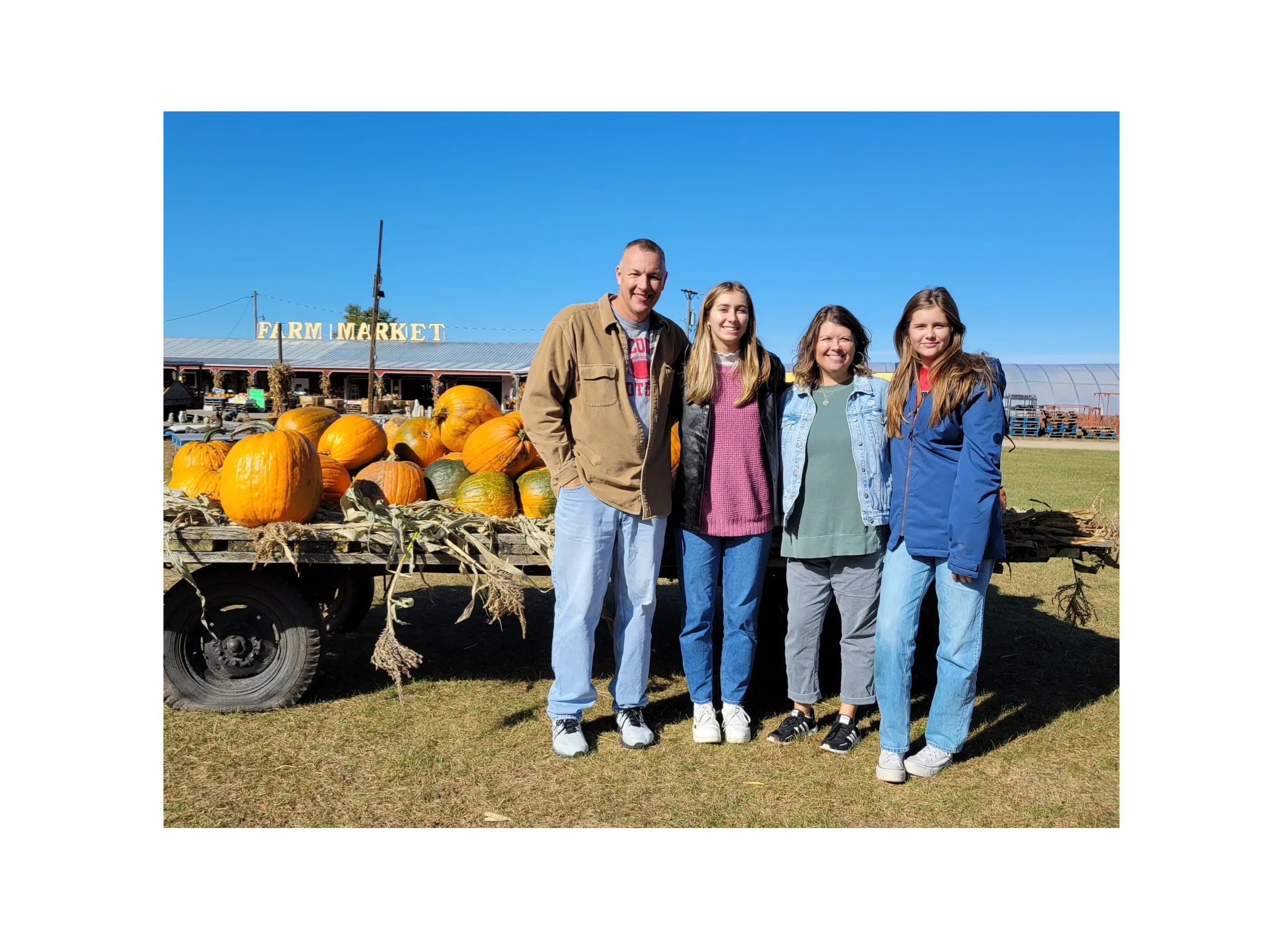 Group of people standing near a cart with pumpkins