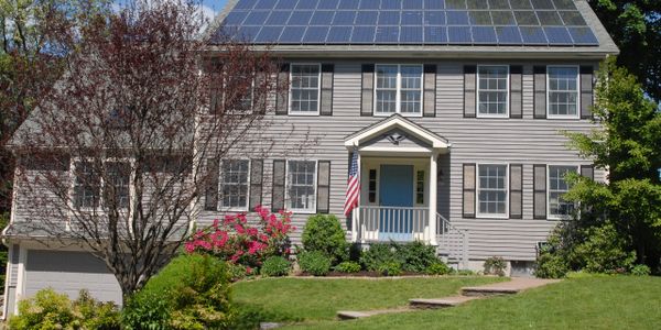 A suburban house with solar panels and an American flag.