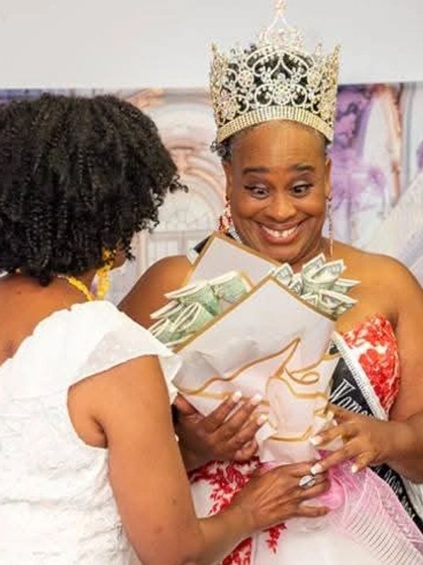 Woman crowned, holding money bouquets, smiling happily.