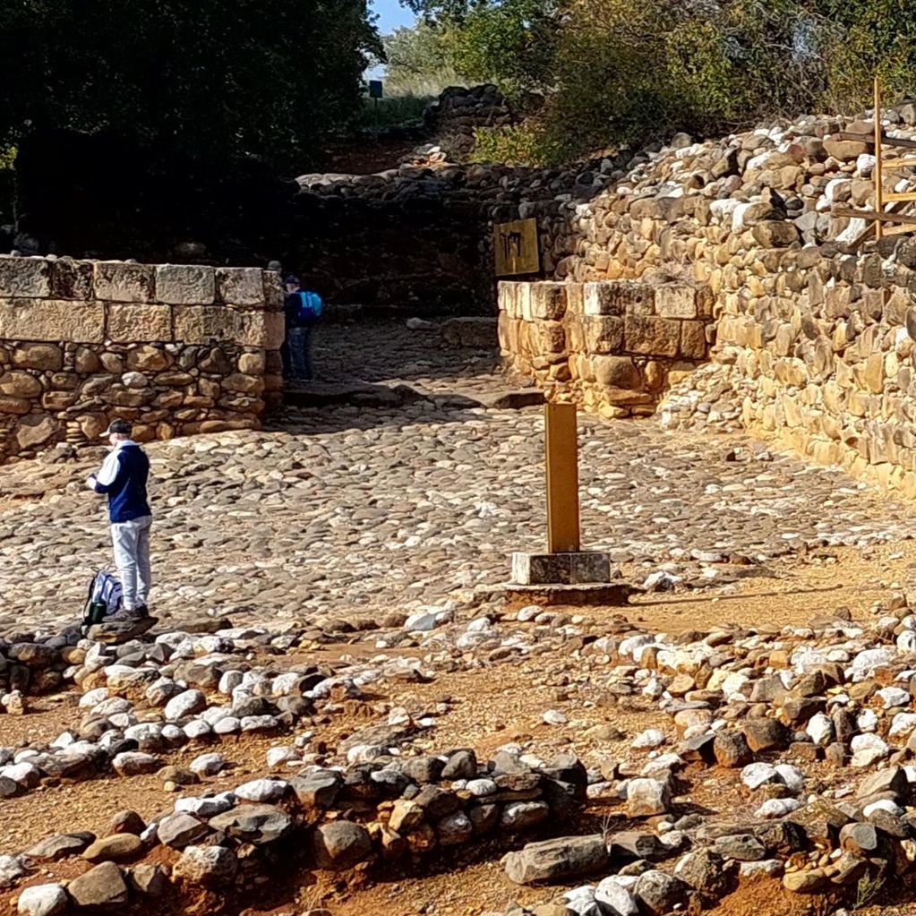 Ancient stone ruins with visitors exploring the site on a sunny day.