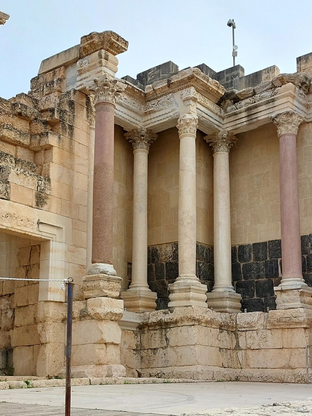 A child stands near ancient stone columns and arches in a historic site.