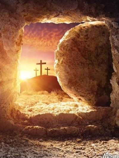 View from inside a tomb looking out at three crosses at sunrise.