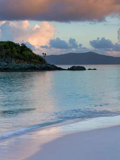 Calm ocean waves gently touching a sandy beach during sunset.