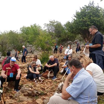 Group of people resting on rocky terrain during a hike.