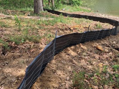 A silt fence installed along a water body to control erosion.