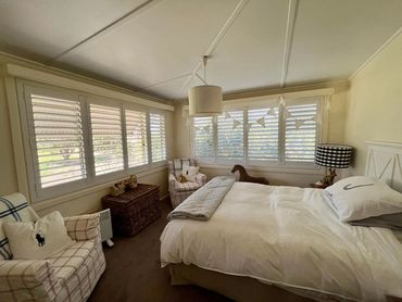 A cozy bedroom with white shutters and decor.