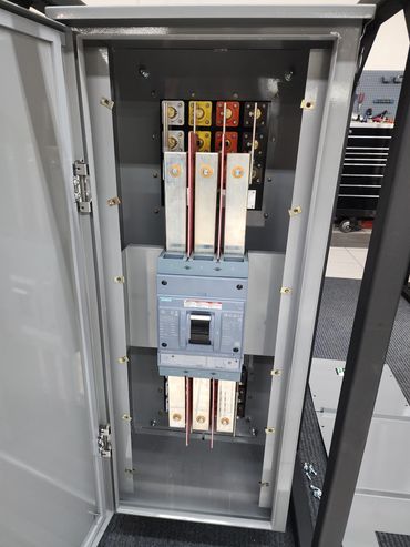 Open electrical panel with circuit breaker and busbars inside.