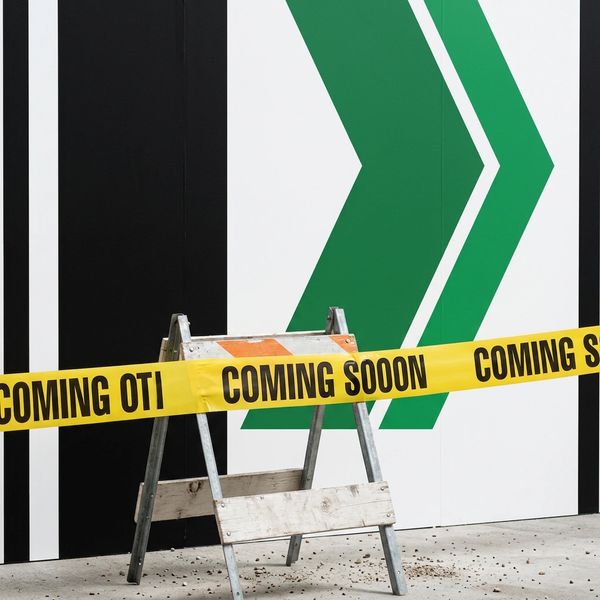 Construction barricade with "COMING SOON" tape in front of a green and black wall.