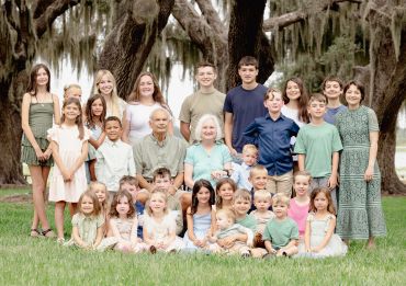 Large family group photo outdoors under trees.