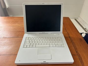 White MacBook laptop on a wooden table.