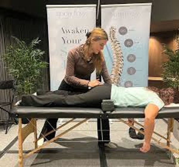 Chiropractor adjusting patient's back on treatment table.