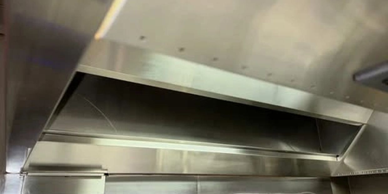 Stainless steel commercial kitchen exhaust hood installed.