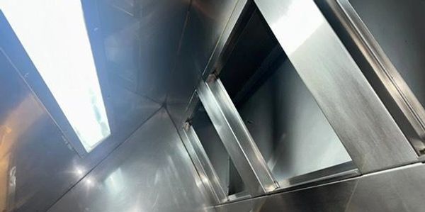Shiny stainless steel kitchen ventilation hood with bright lighting.