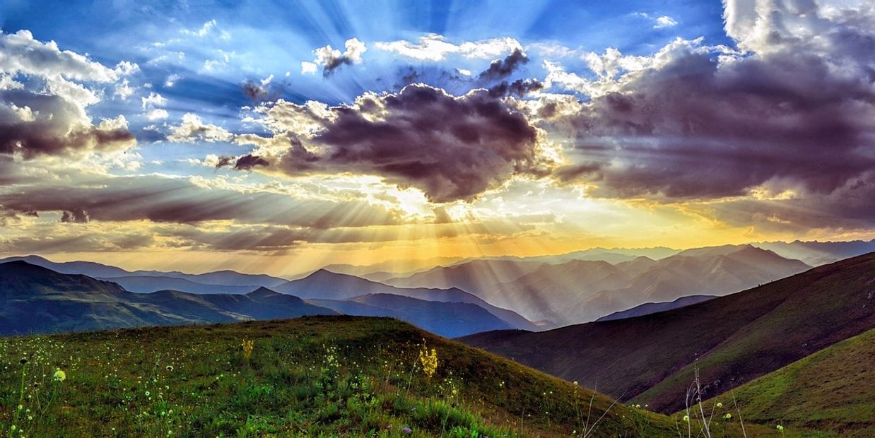 Scene of sun behind clouds above a valley, meant to inspire hope that hypnotherapy will work for you.