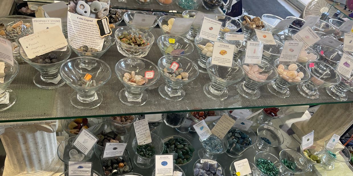 Display of various tumbled gemstones with informational labels.
