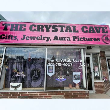Front view of The Crystal Cave storefront with a bright pink banner.