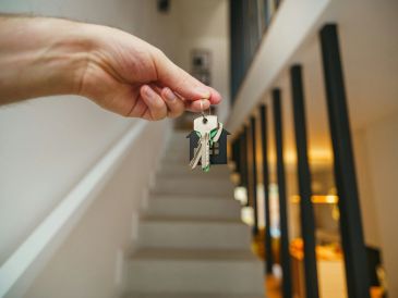 Hand holding house-shaped keychains in a modern home.