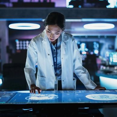 Scientist in a lab coat analyzing brain scans on a large touchscreen table.