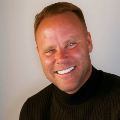 Smiling man in a black sweater against a plain background.