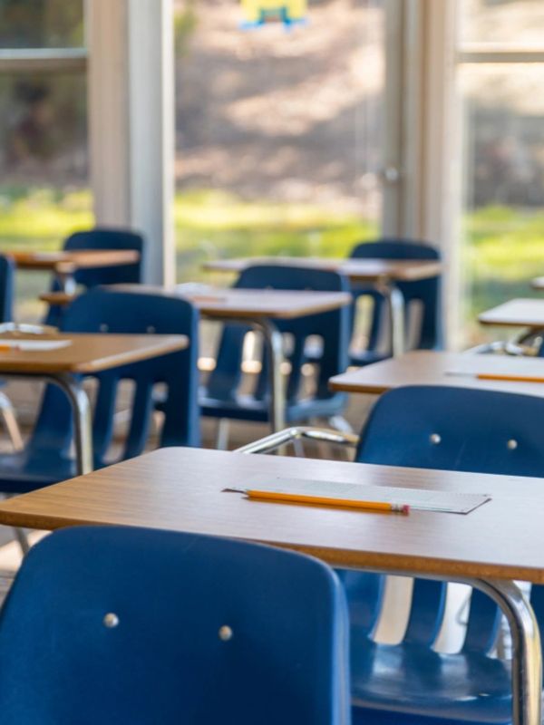Empty classroom desks with pencils and papers ready for students.
