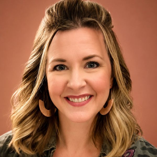 Smiling woman with wavy blonde hair and wooden earrings.