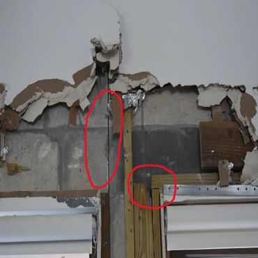 Damaged wall with exposed concrete and insulation, circled for repair focus.
