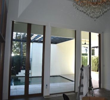 Modern glass doors open to a bright outdoor pool area.