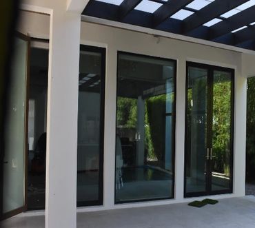 Modern glass doors and windows with black frames in a bright outdoor space.