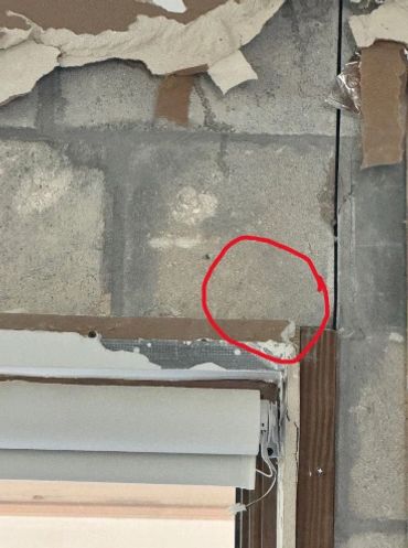 Wall corner with peeling paint and a red circle marking a spot.