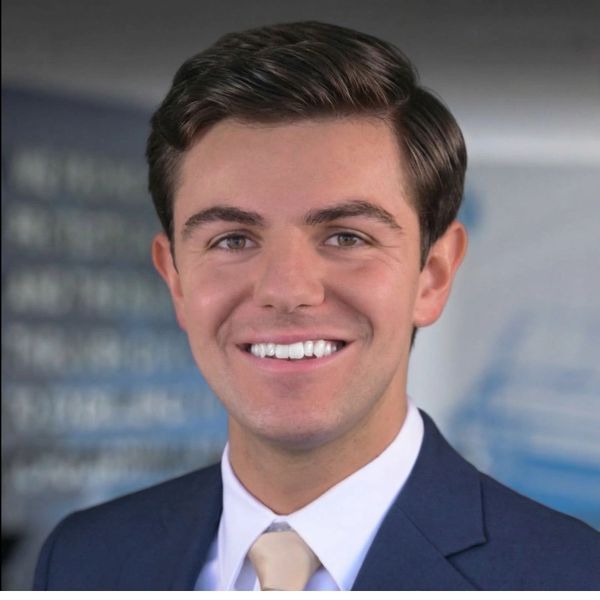Young man in a suit smiling at the camera.