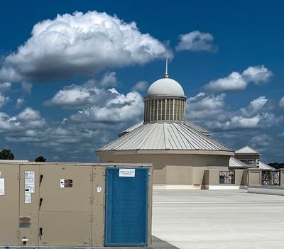 Rooftop HVAC unit with a rounded building and blue sky in the background.