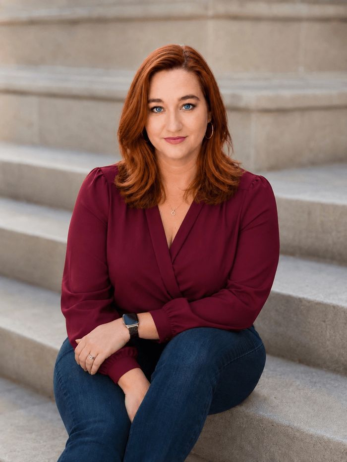 A woman with red hair sitting on stone steps.