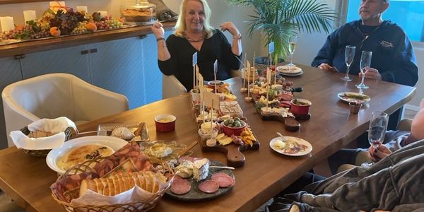People enjoying a charcuterie spread at a dining table.