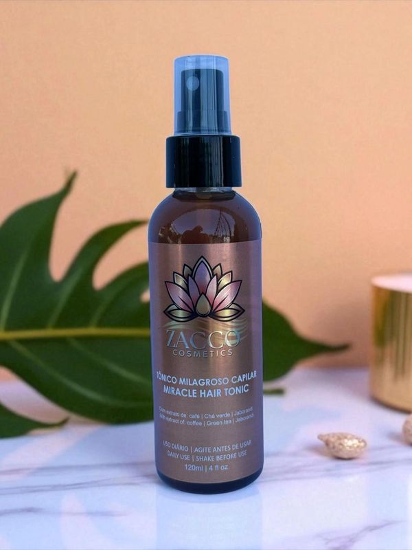 Zacco Cosmetics Miracle Hair Tonic bottle on a marble surface with green leaf background.