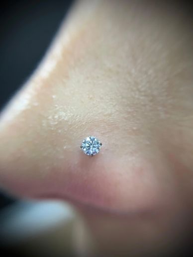 Close-up of a sparkling nose stud piercing on skin.