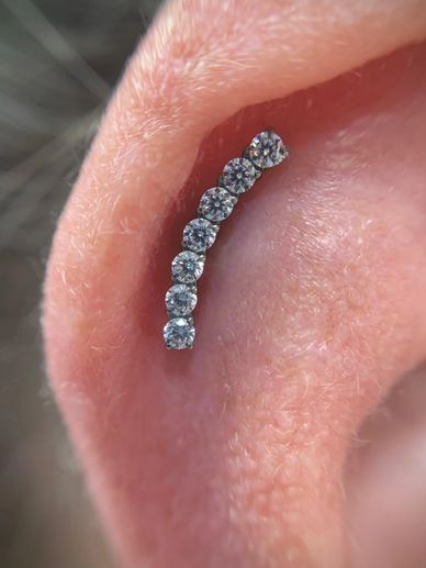 Close-up of an ear adorned with a curved row of seven sparkling diamond earrings.
