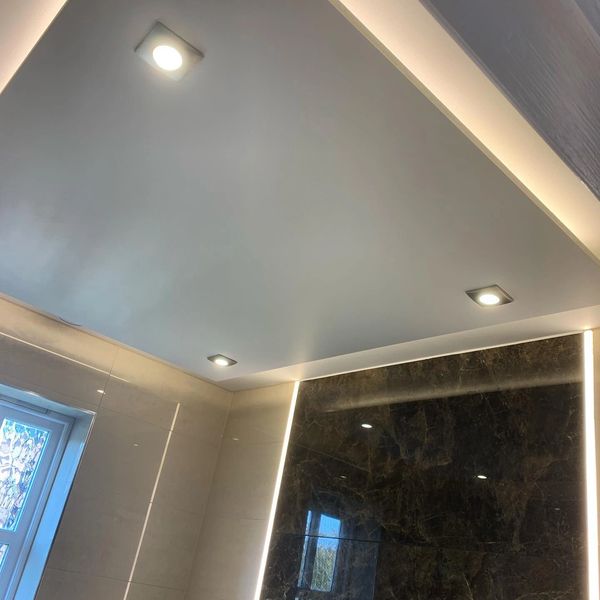 Modern bathroom ceiling with recessed and strip lighting.