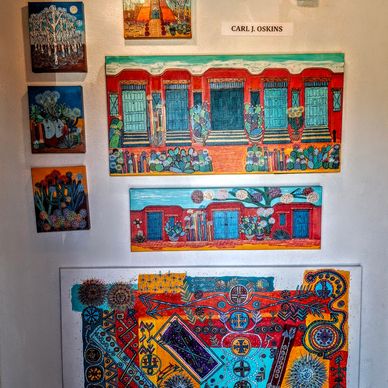several acrylic paintings on a wall by artist Carl Oskins.