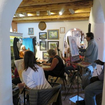 photo of a workshop meeting with artists sketching and a live model posing for them
