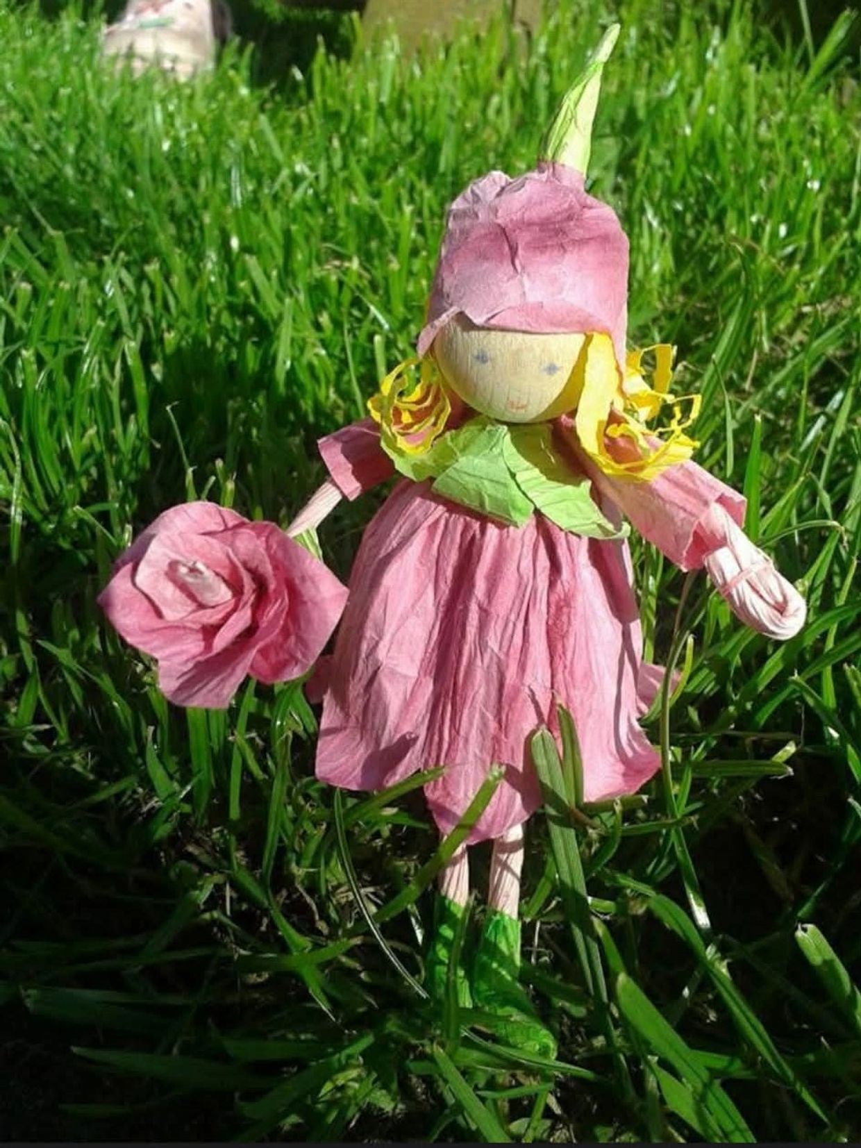 Handmade paper doll in a grassy field.