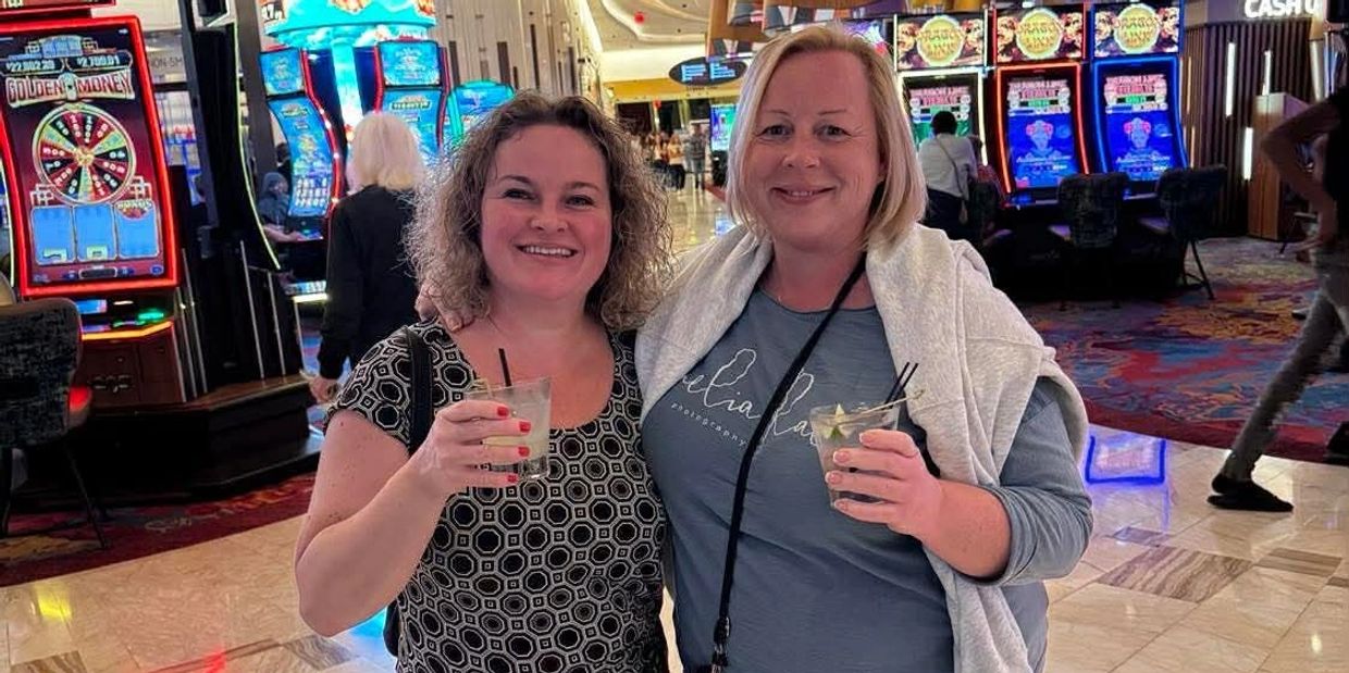 Two women smiling with drinks in a casino.
