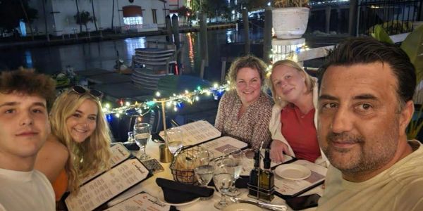 Group of five people dining outdoors at night.