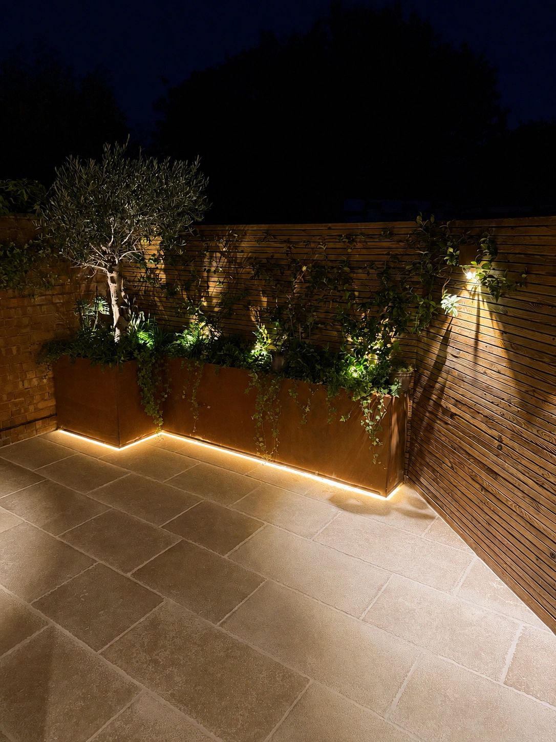 Antique Egyptian limestone paving, In-Lite lighting system & CorTen planters with dense planting of 