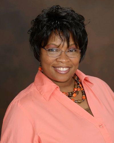 Headshot of a woman in a peach color shirt 