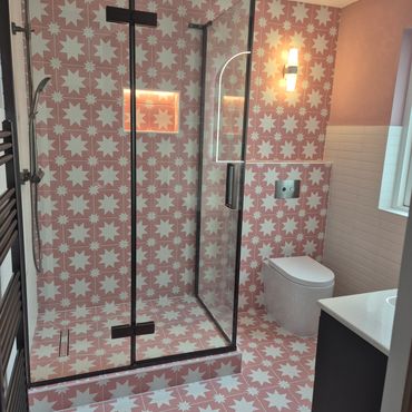 Modern bathroom with pink star-patterned tiles and a glass shower.
