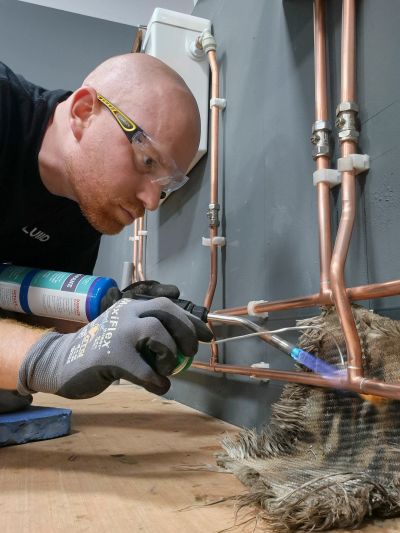 Man soldering copper pipes with a torch.