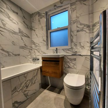 Modern bathroom with marble walls and wooden vanity.