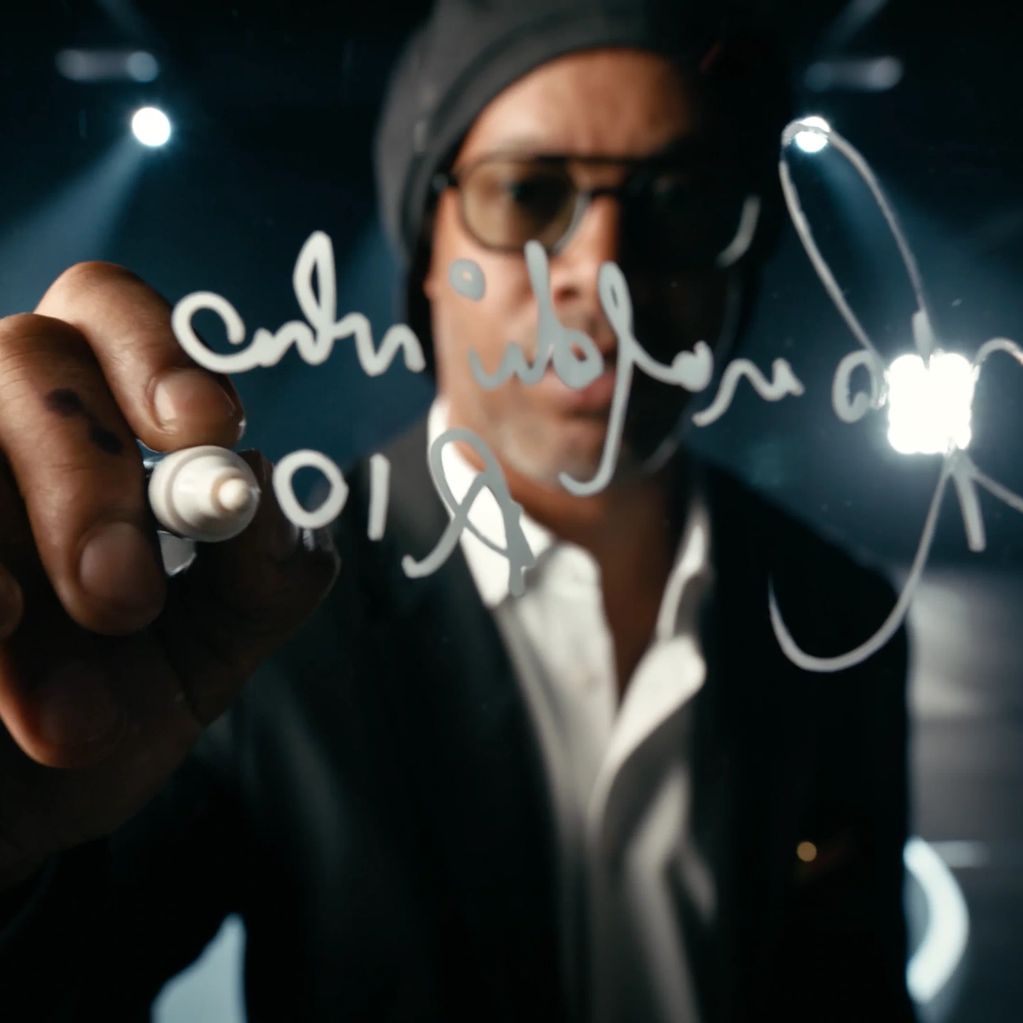 Man writing on transparent glass with a marker in a dark room.