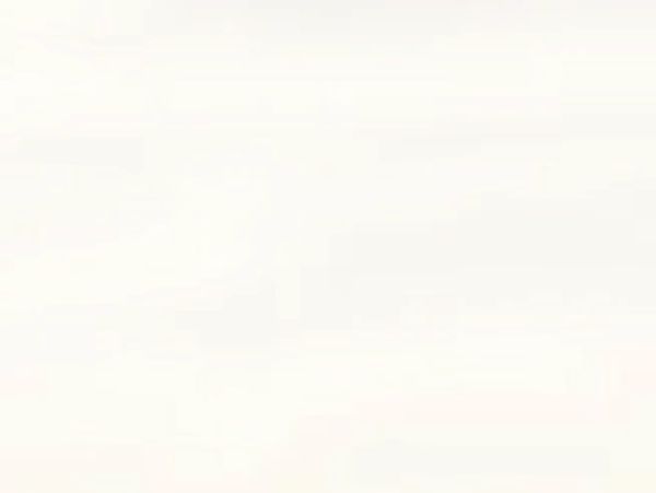 Smiling woman with curly hair sitting barefoot on rocks near a grassy shoreline.