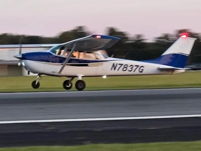 Small blue and white airplane landing at sunset.